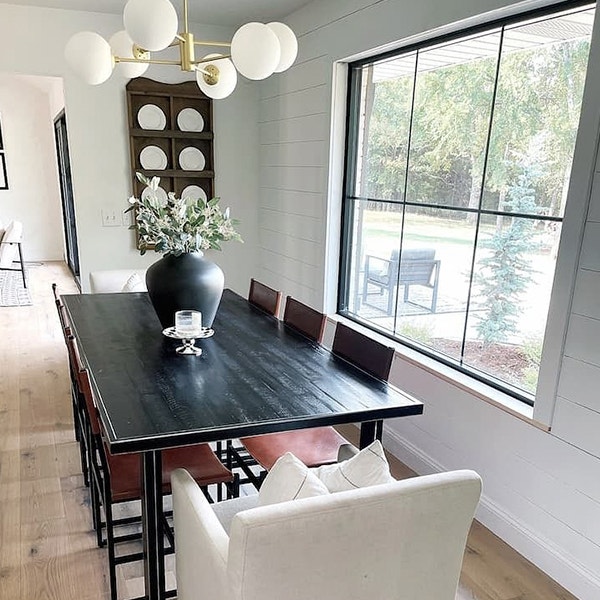 A large black-trimmed picture window beside a black wood table with contemporary design