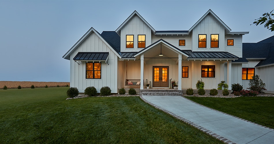 An Iowa farmhouse-style new construction home with black-framed windows and a two-panel 3/4 light wood entry door.