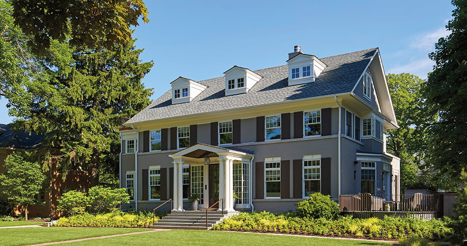 A traditional two-story home, complete with double-hung windows, shutters, and a columned entry.
