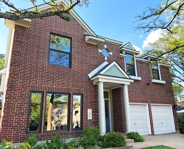 Curbside view of traditional Austin brick home with newly installed Pella brown vinyl windows.