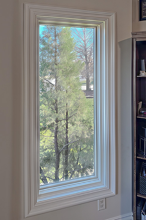 A fixed interior almond window frames a view of trees in a Wichita, KS home.