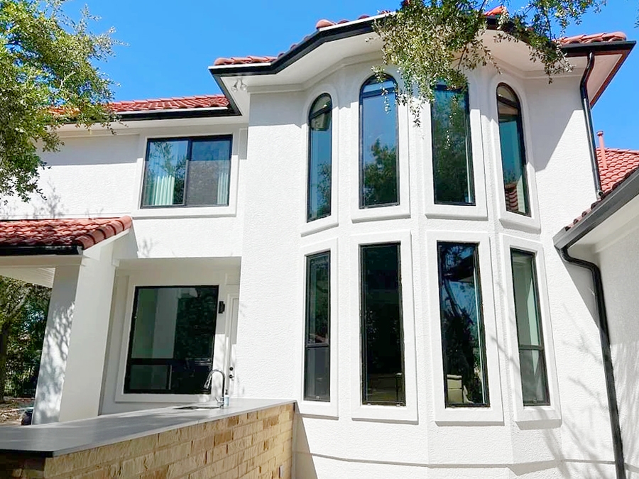 Backyard view of Spanish-style Austin home with energy efficient windows reducing energy cost in Texas heat. 