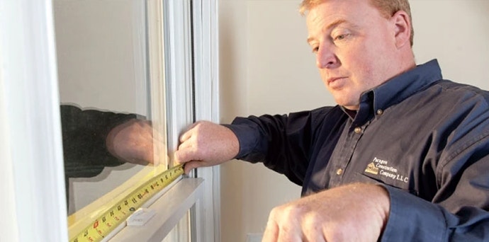 A Pella team member is measuring windows for replacement