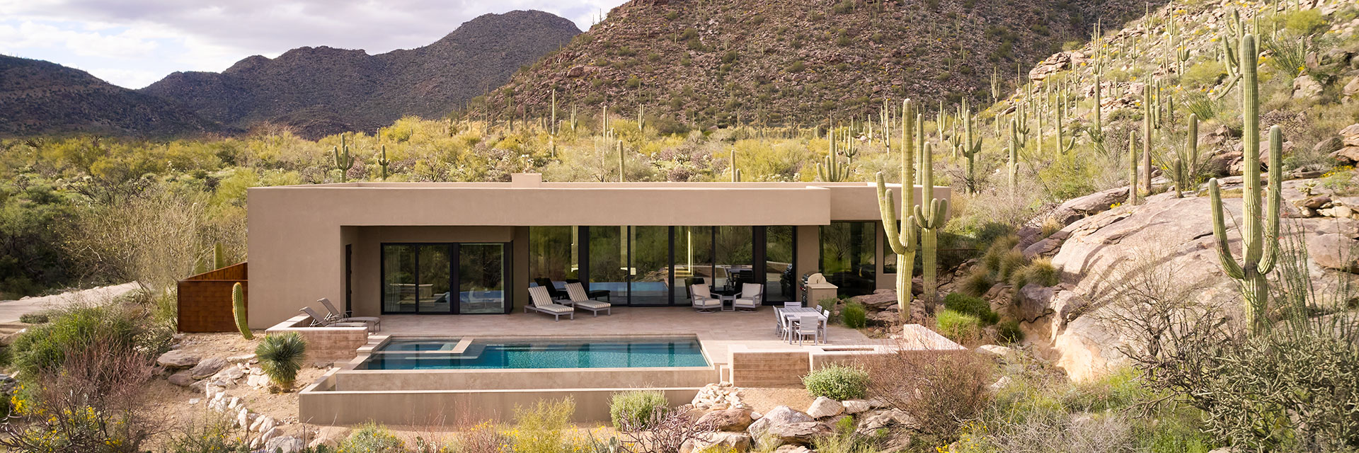 a single-story home in the middle of a western desert, surrounded by cactus