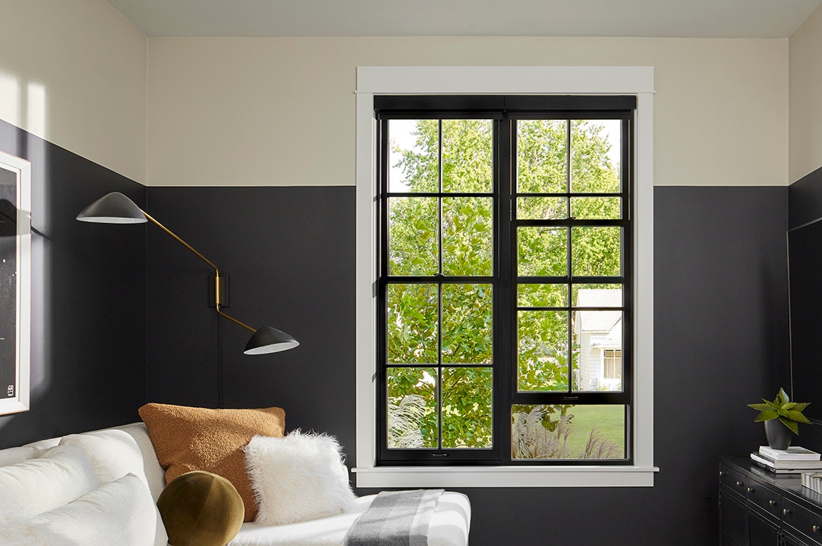 A modern kitchen with bay windows, tan brick wall, and a stylish countertop.