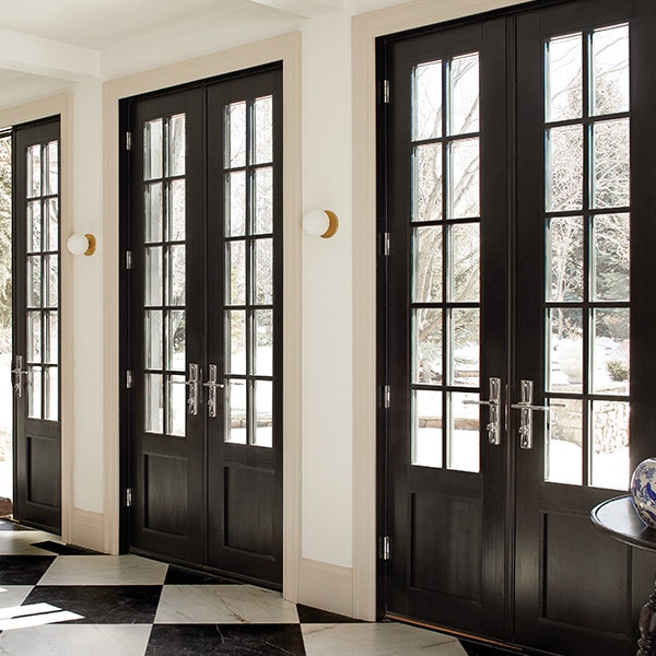 Five black hinged doors in dining room with wood table