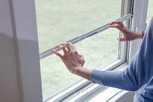 a woman using a retractable screen on a lifestyle series hung window