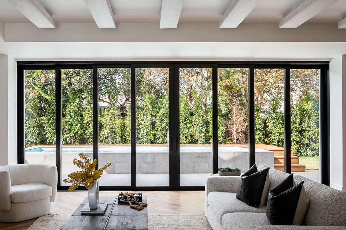 A modern living room with black sliding doors opening to a pool view, showcasing stylish sliding door ideas.