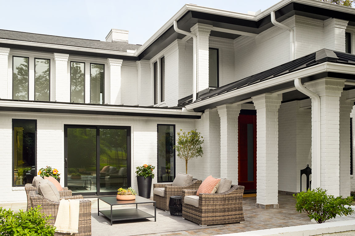 Black sliding patio door on a white brick home with outdoor seating.