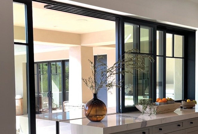 black pass-through windows open to the exterior patio from the kitchen