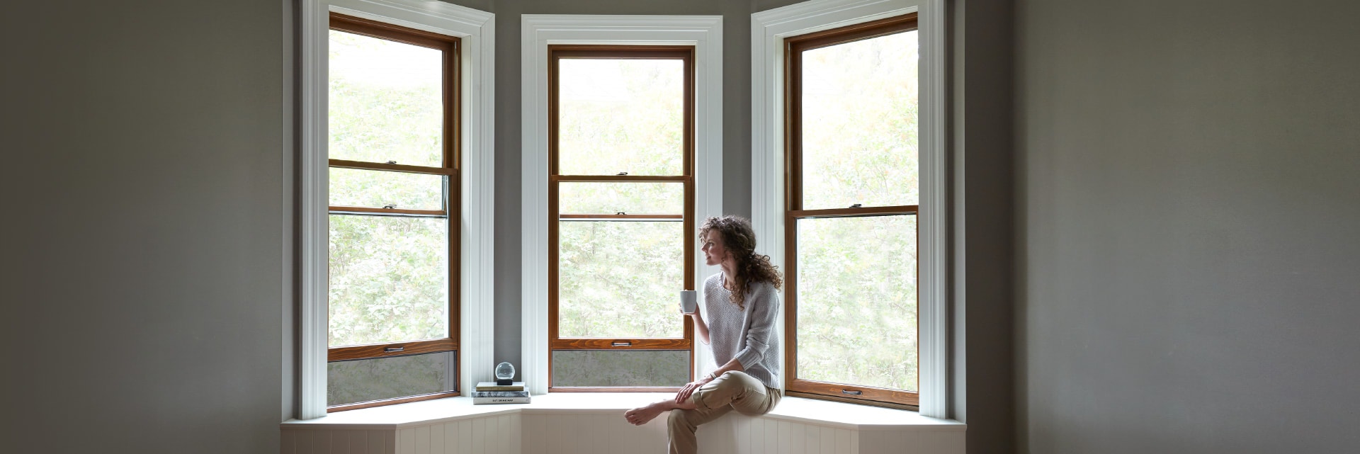 woman sitting on a window seat with three double-hung reserve windows surrounding her