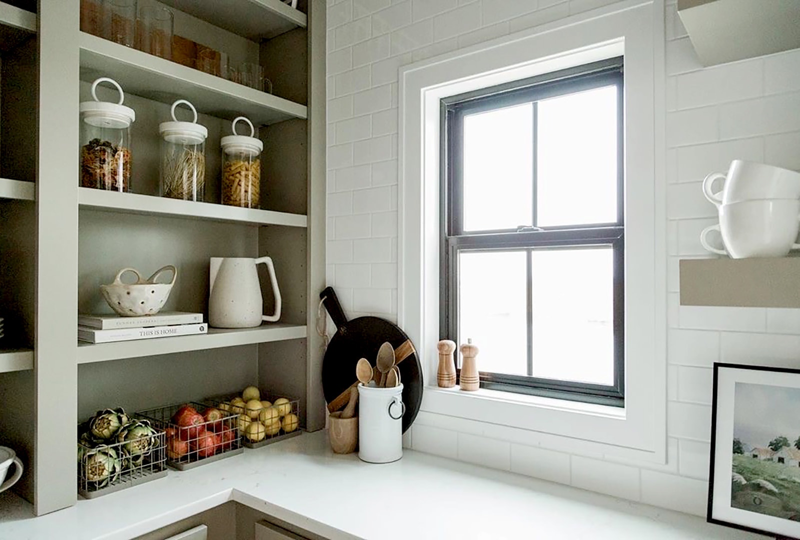 A black single-hung window in the corner of a farmhouse-style kitchen.