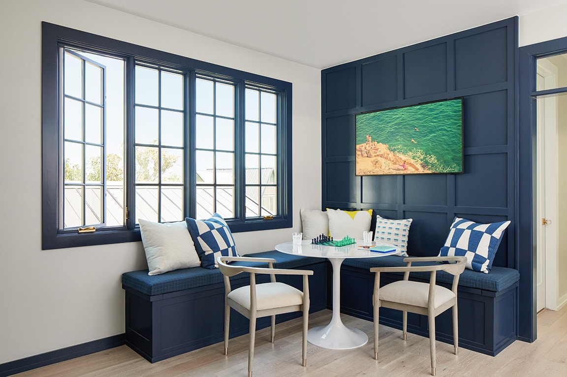 A cozy nook featuring blue windows and a round table with chess pieces.