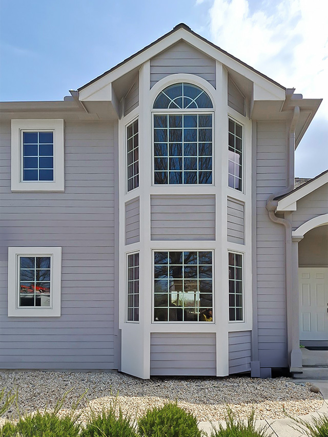 A modern home exterior featuring large energy efficient windows and a light gray facade.