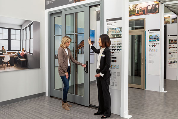 Two women are discussing a new Pella sliding patio door in a showroom.