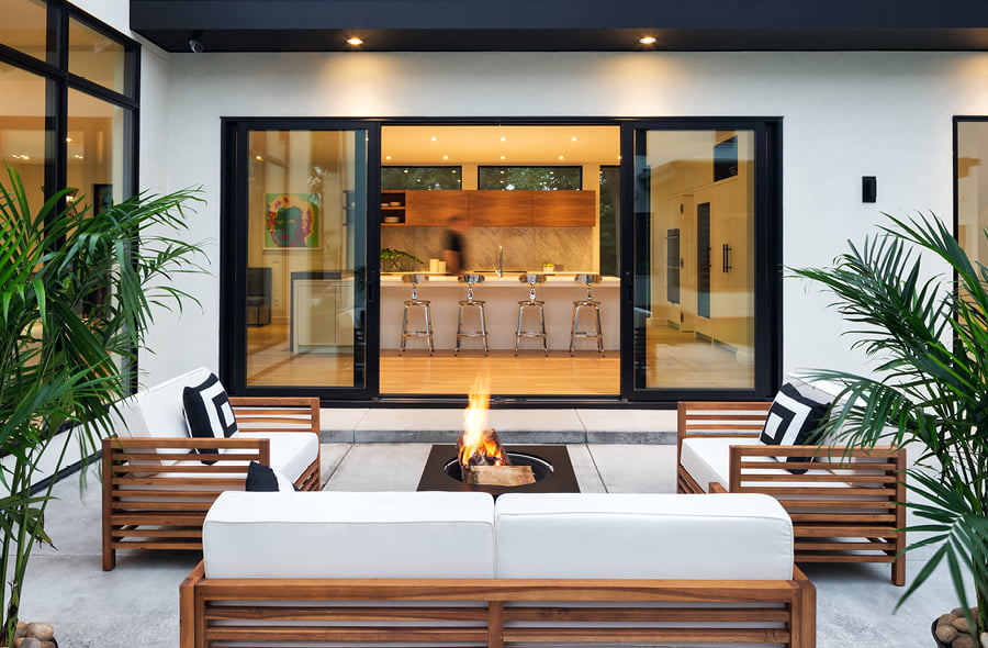 Black sliding patio doors in an outdoor entertaining space with a fireplace and furniture on the deck
