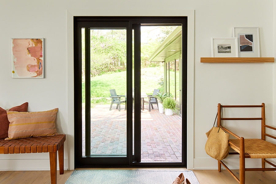 black sliding patio door open to a brick-floored patio