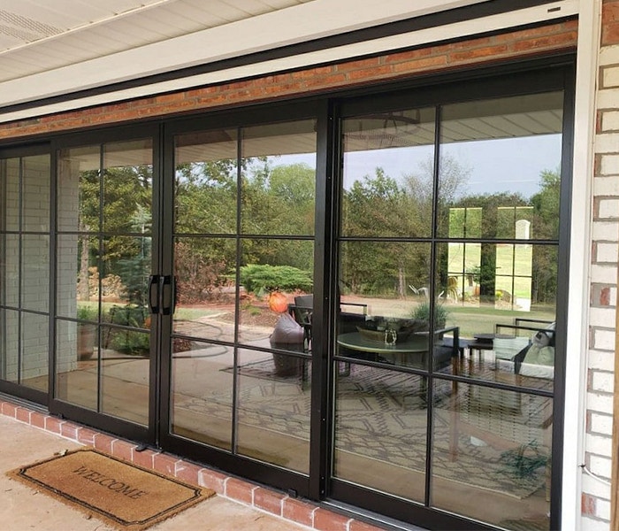 The exterior of a home that is reflecting off the glass of black sliding patio doors