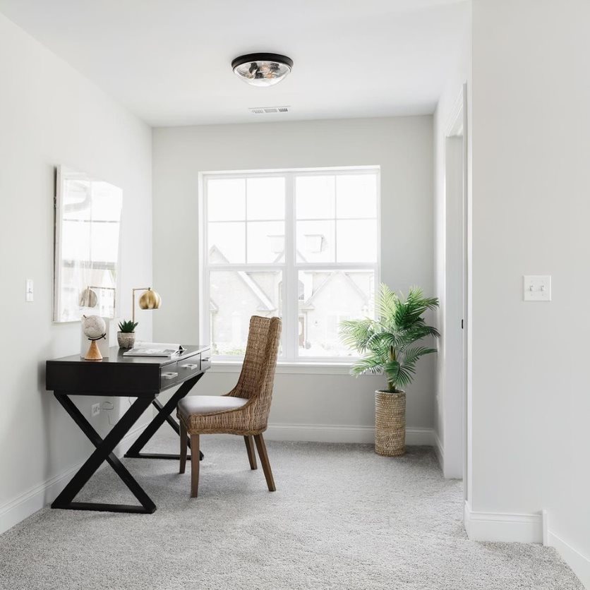 Home office windows next to a desk and chair add natural light and fresh air to the work space.