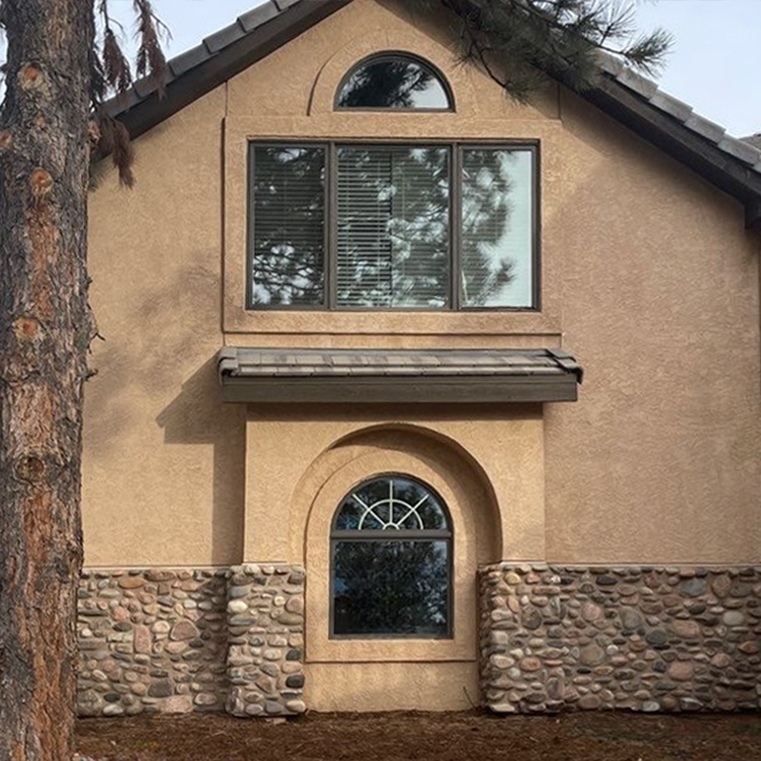 Exterior of Colorado Springs Pueblo revival home with outdated windows.