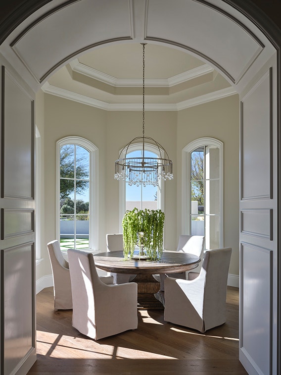 Formal dining room overlooking water featuring white windows with a traditional grille pattern.