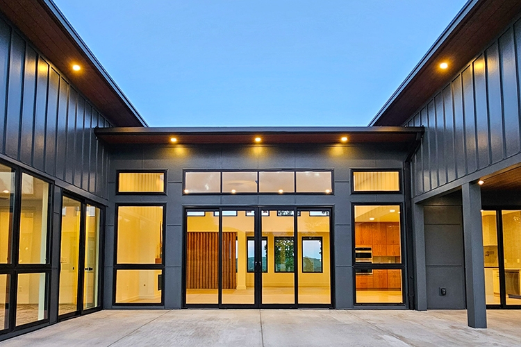 Patio view of floor-to-ceiling black windows and patio doors.
