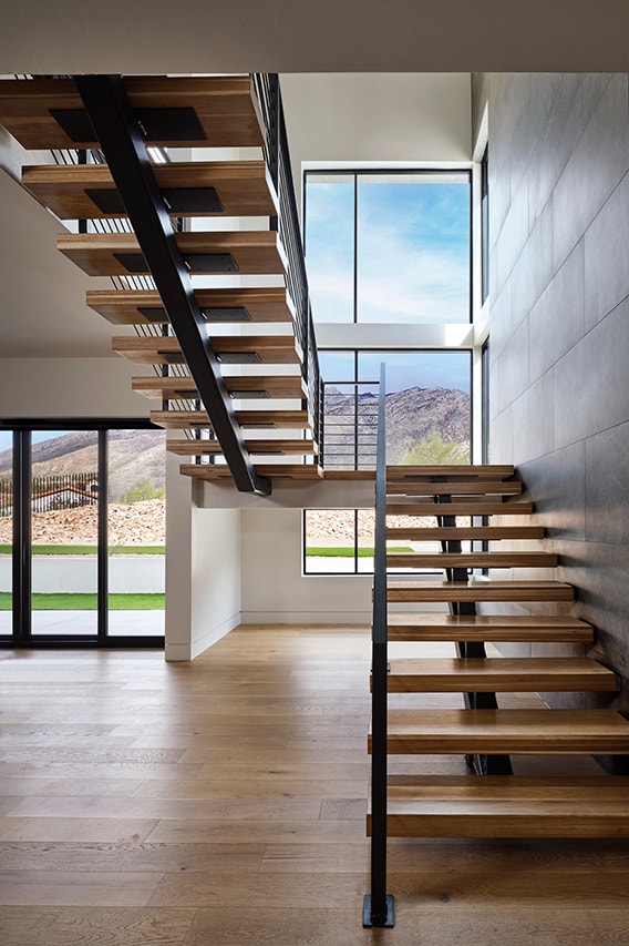Floating wooden staircase with black windows and sliding patio doors.