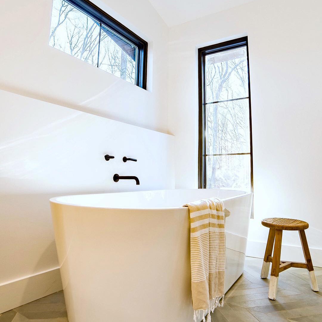 white bathroom with black windows framing a free standing tub