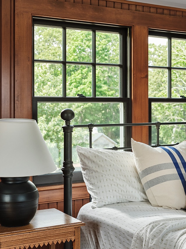 Bedroom with wood trim and double-hung windows providing natural light.