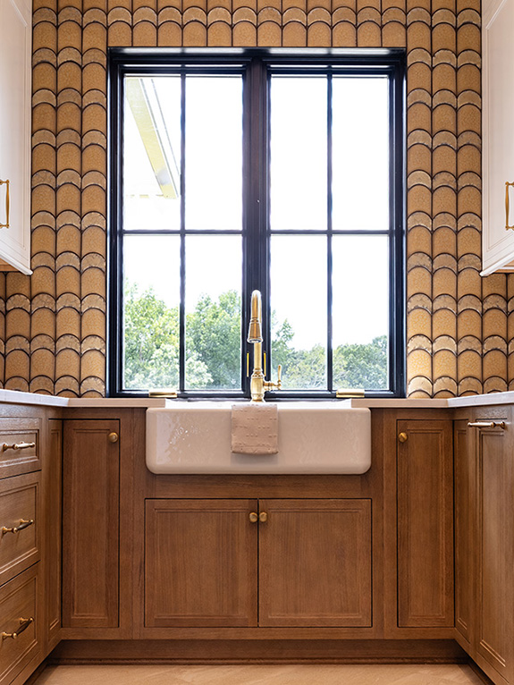 Modern kitchen with a large farmhouse sink, wooden cabinets, and a big window offering an outdoor view.