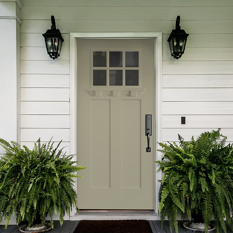 exterior view of a craftsman light front entry door with large ferns on each side