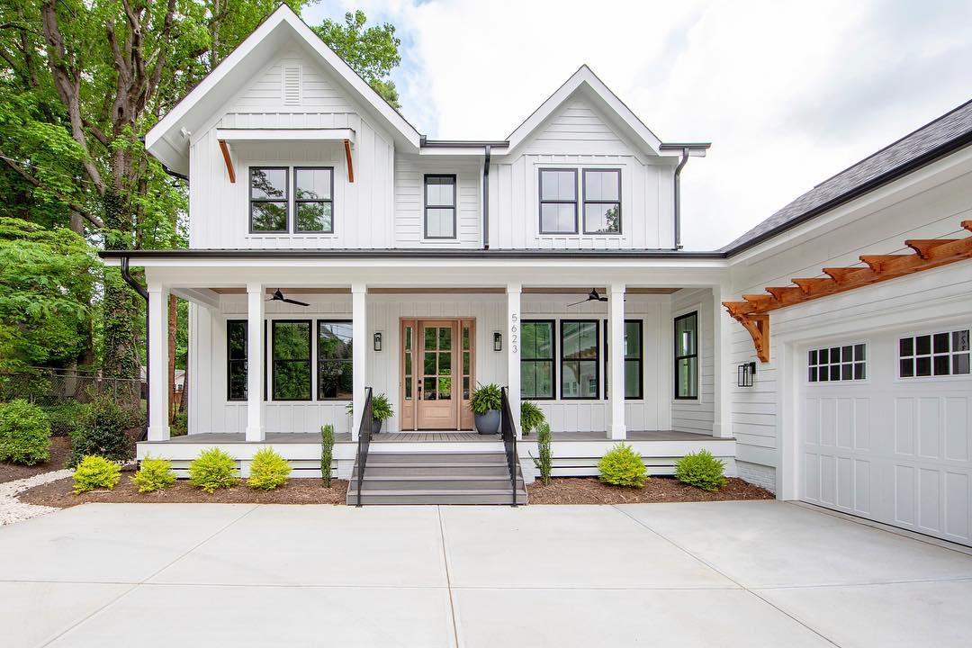 Two story modern farmhouse with white siding, black windows, and a wood front door