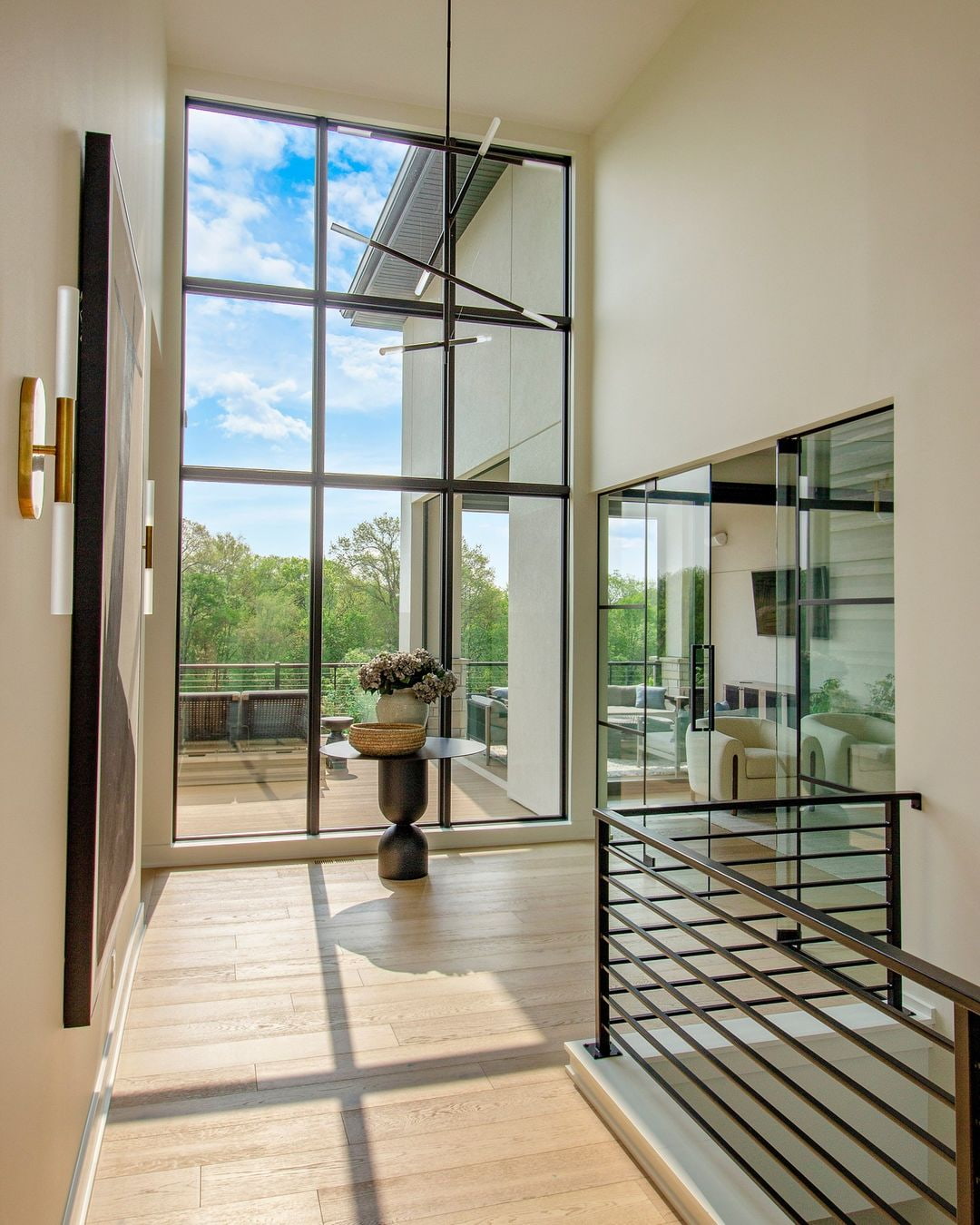 Floor-to-ceiling windows brighten a staircase area and overlook an outdoor deck beyond.