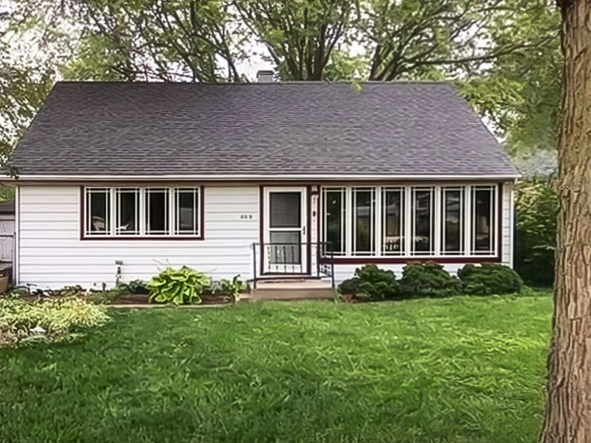 A simple white home with a white screen door and wood casement windows.