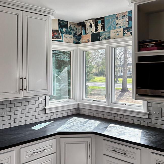 A bright kitchen corner with white cabinets and large casement windows in Kansas City.