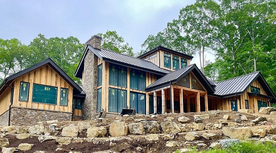 the back exterior of a large wood home with floor-to-ceiling windows