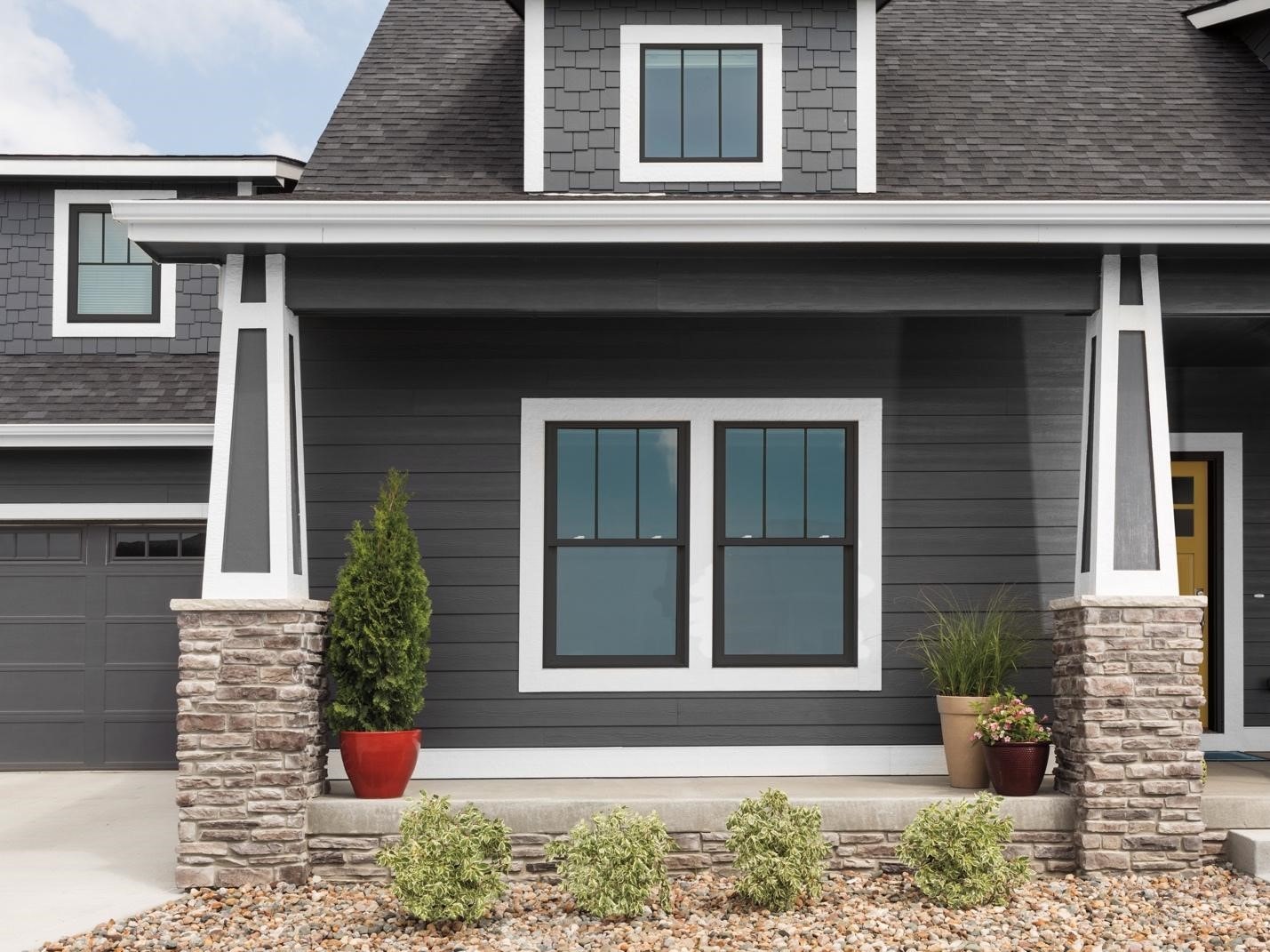 Exterior view of a gray craftsman-style home with black vinyl windows and white trim.