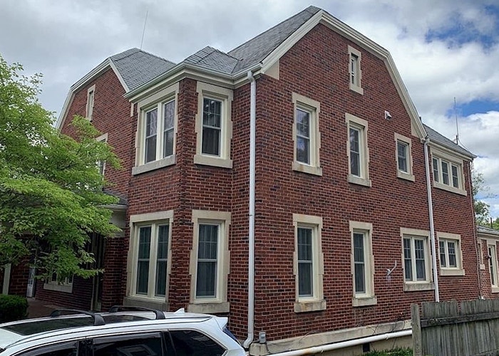 the side view of a large historic brick home with new white vinyl windows