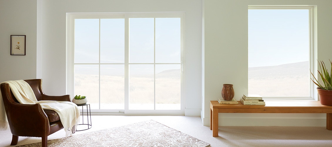 living room in tan with white carpet and white vinyl windows and sliding door