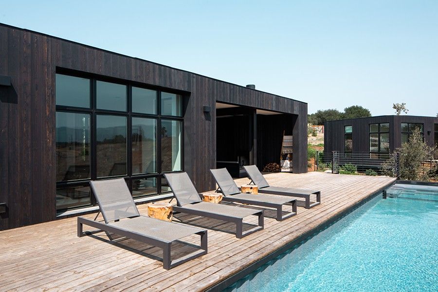 Wood exterior building with black frame windows next to an outdoor pool