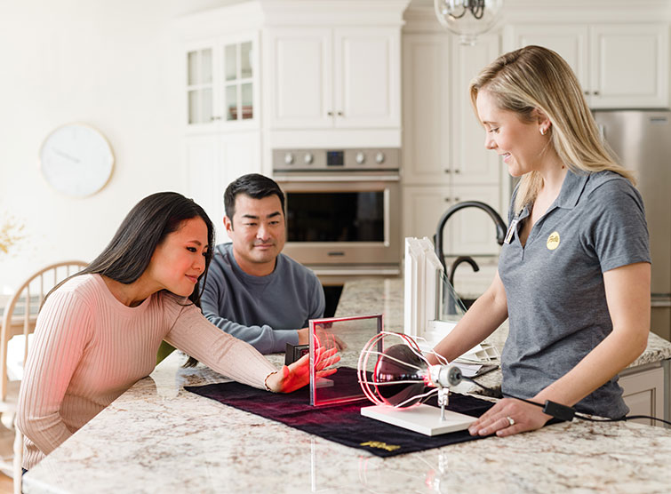 A Pella saleswoman is demonstrating thermal affects on window materials to a young couple