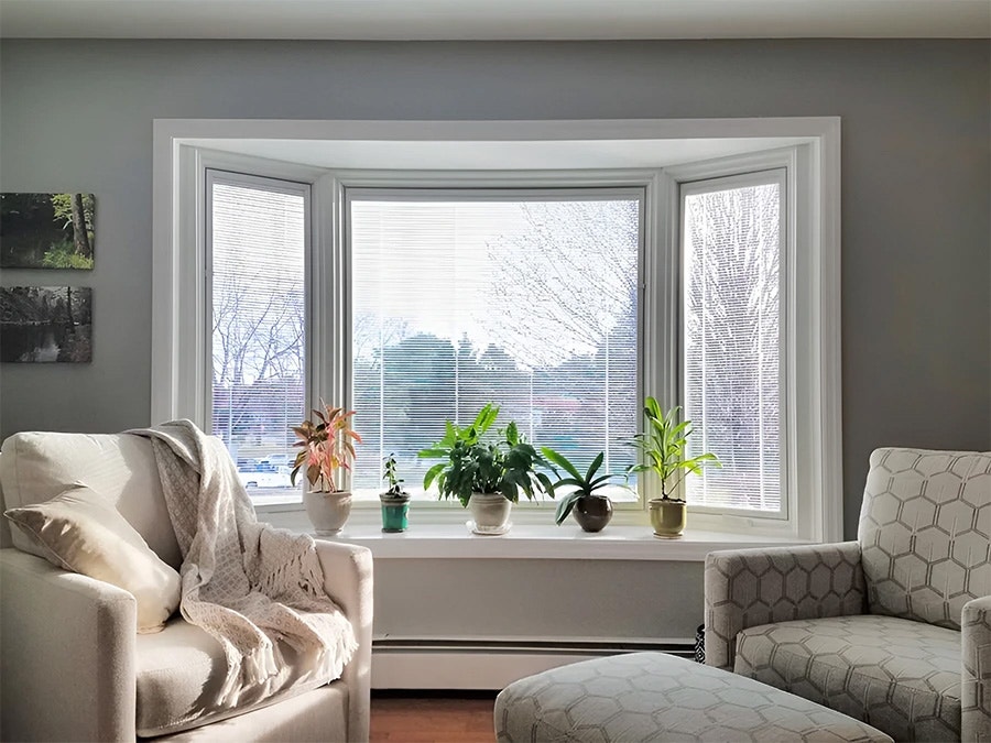 A living room showcasing blinds between the glass bay window, after transformation.