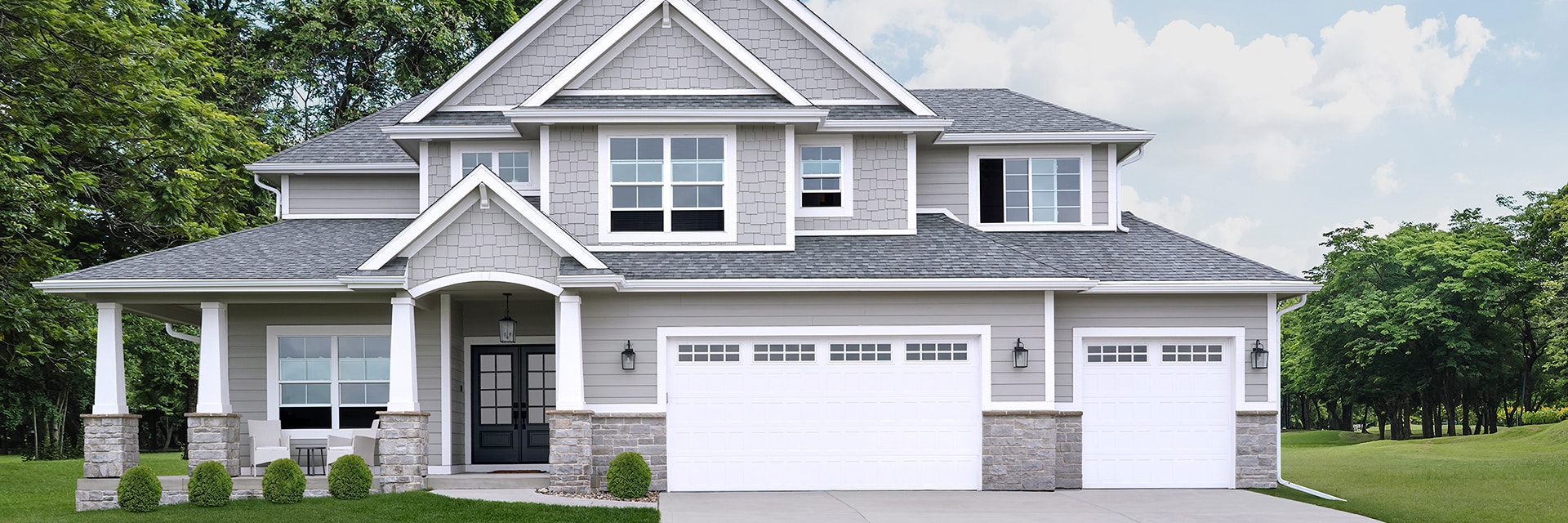 A large gray home with white windows and a white garage door.