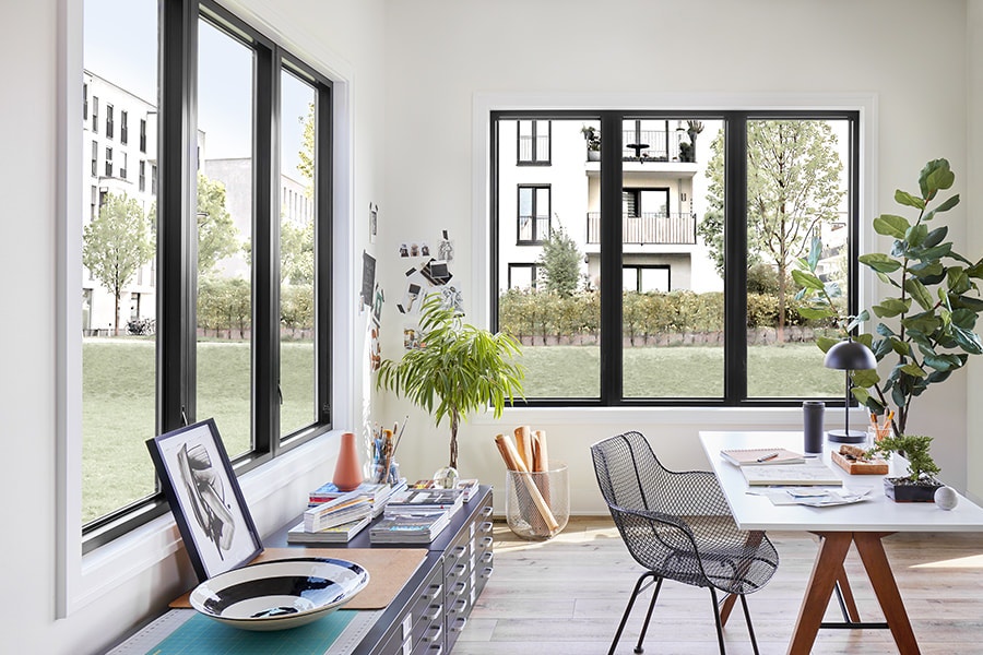A modern home office with three-wide casement window configurations on each corner wall.