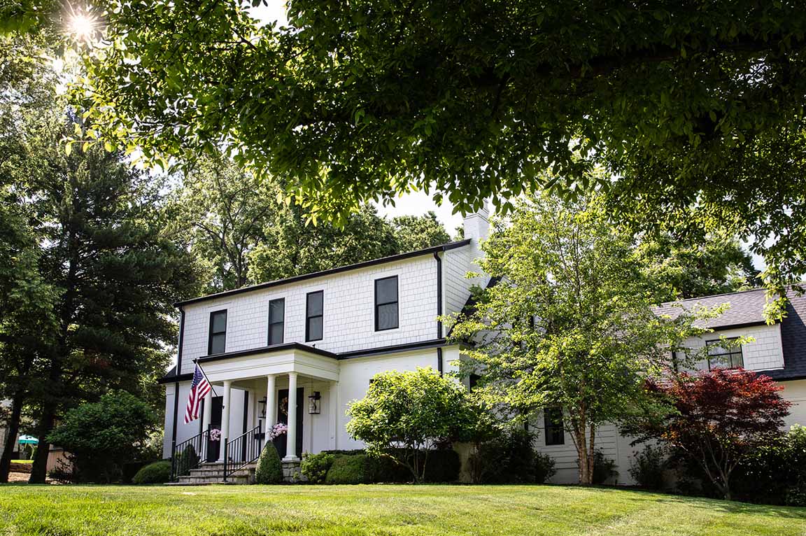 Columbus Worthington colonial home with white siding and black shutters surrounded by lush greenery.