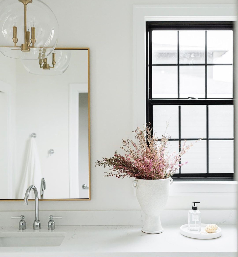 A black window in a light-colored bathroom invites natural light and brightness to the space.