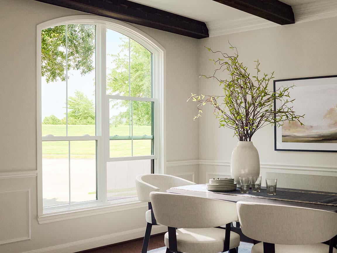 Arched window bringing natural light into dining room interior.