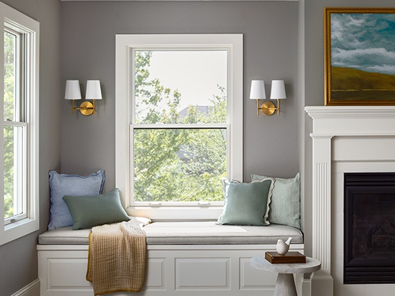 wood double-hung window over a window seat at the corner of a living room