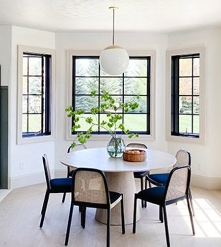 Black casement windows contrast against light interiors in modern breakfast nook.