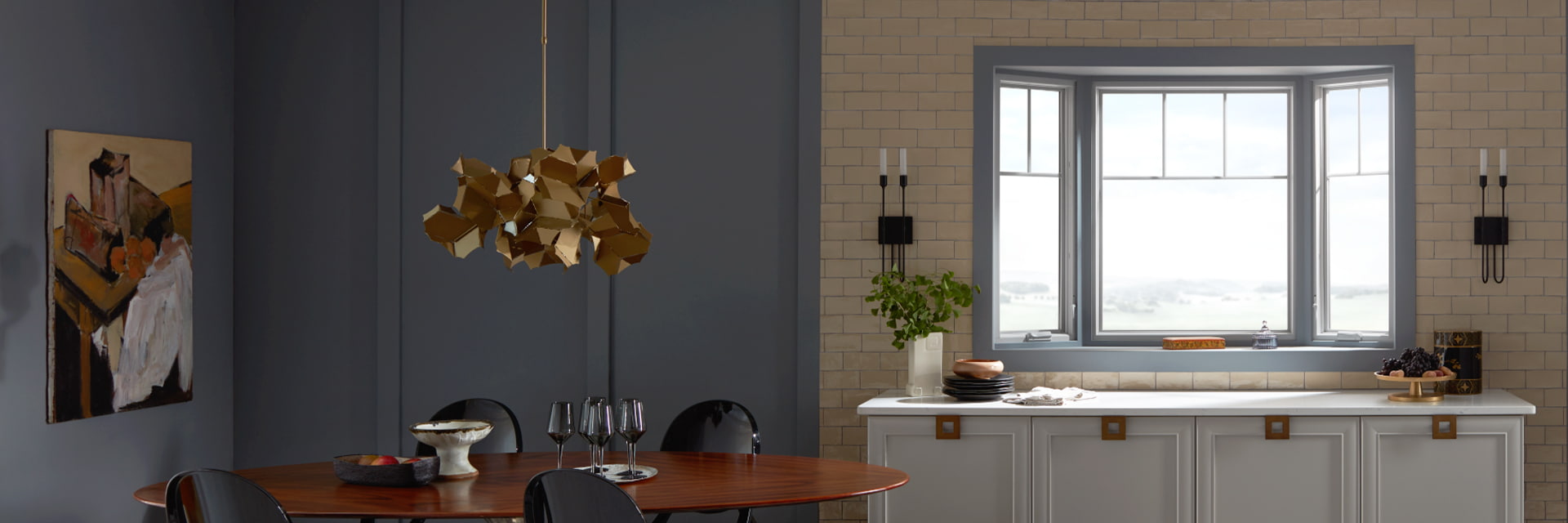 a woman is adjusting her shoe on a bench in front of floor-to-ceiling bow windows with a hinged door in the middle